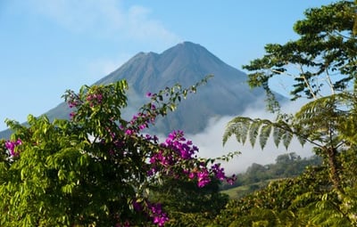 En vulkan omgiven av frodig vegetation och blommor, Arenal volcano Costa Rica